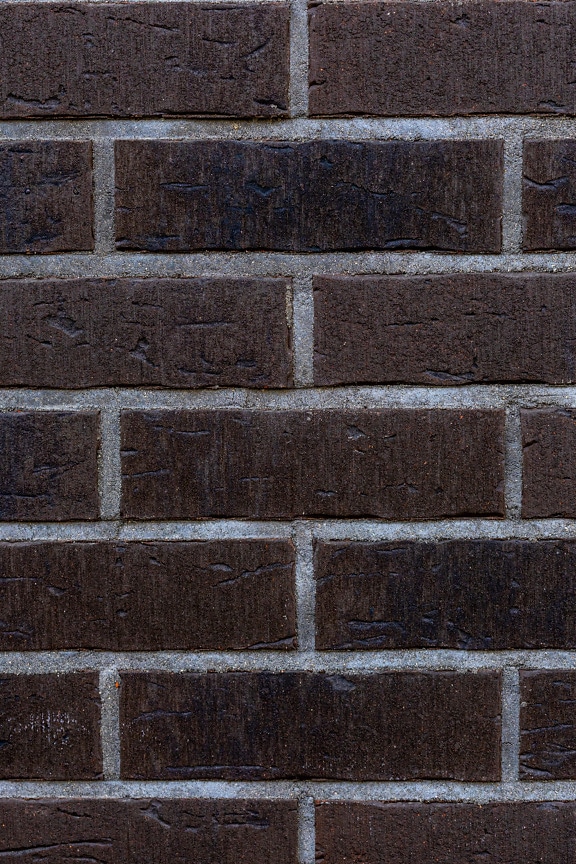 Murvegg med mørkebrun teglstein og grå mørtel