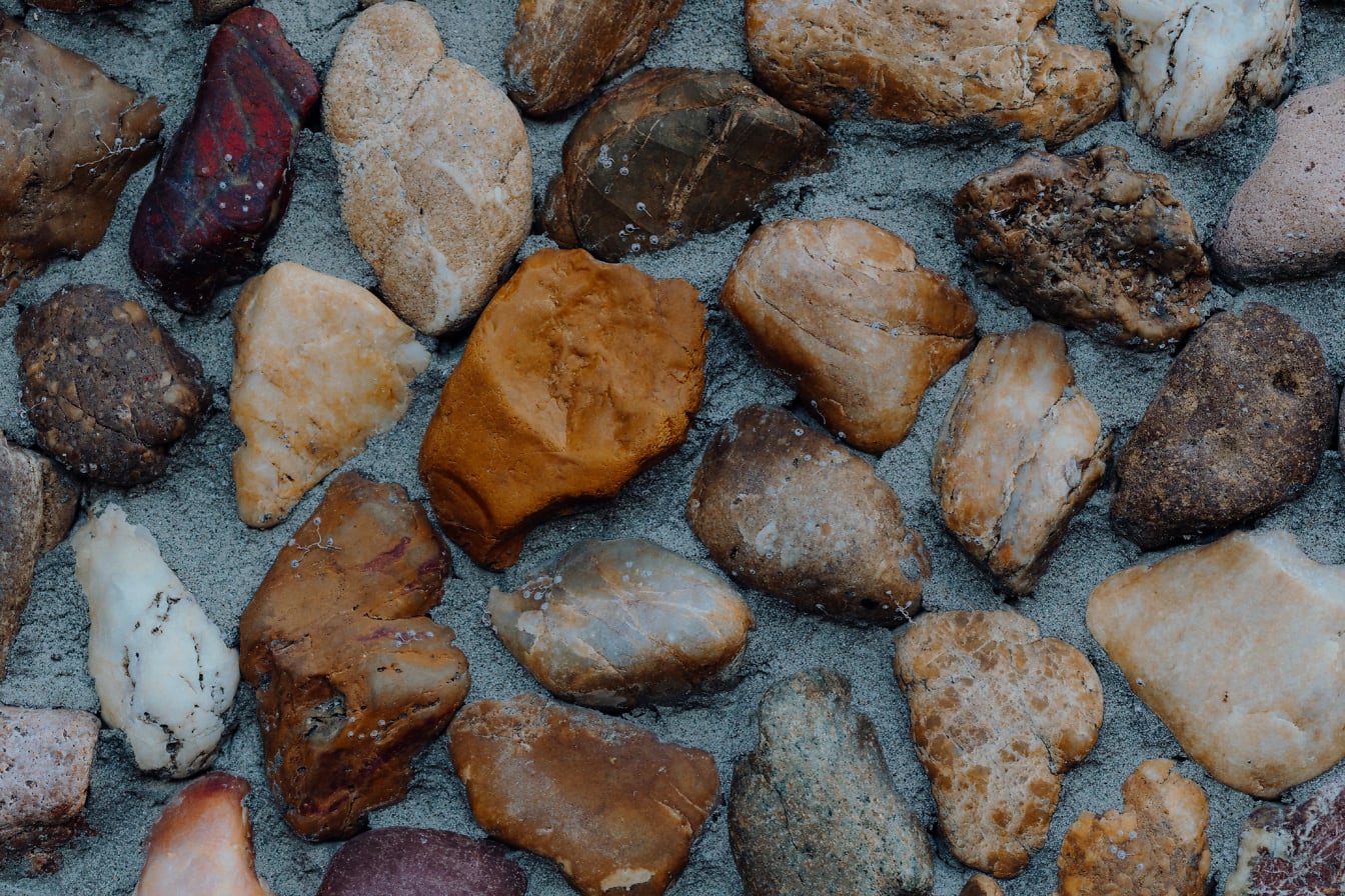 Textuur van geelachtig bruine en roodachtige rotsen op nat zand