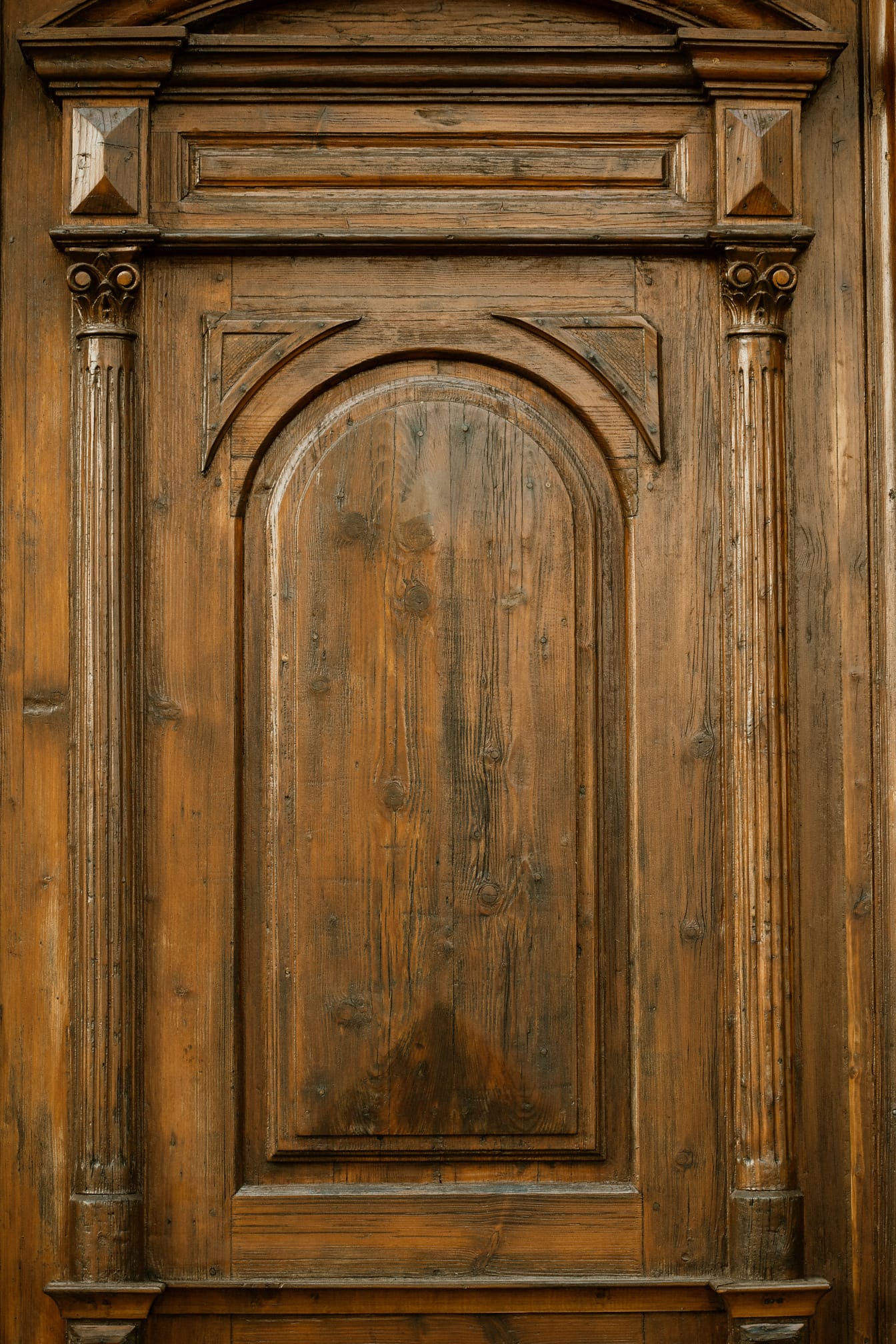 Close-up pintu depan kayu ek buatan tangan berwarna coklat muda dengan dekorasi hias
