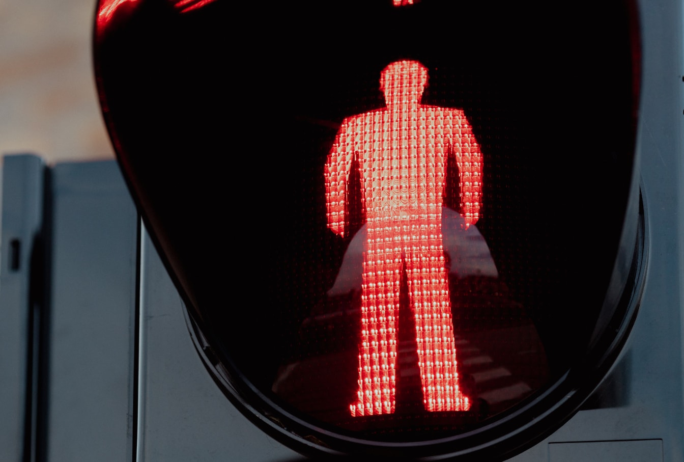 Red traffic light on semaphore with a silhouette of a man