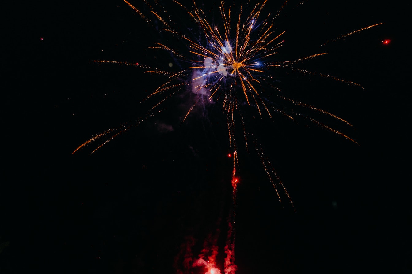 Nažloutlý a načervenalý ohňostroj na obloze při oslavě Nového roku