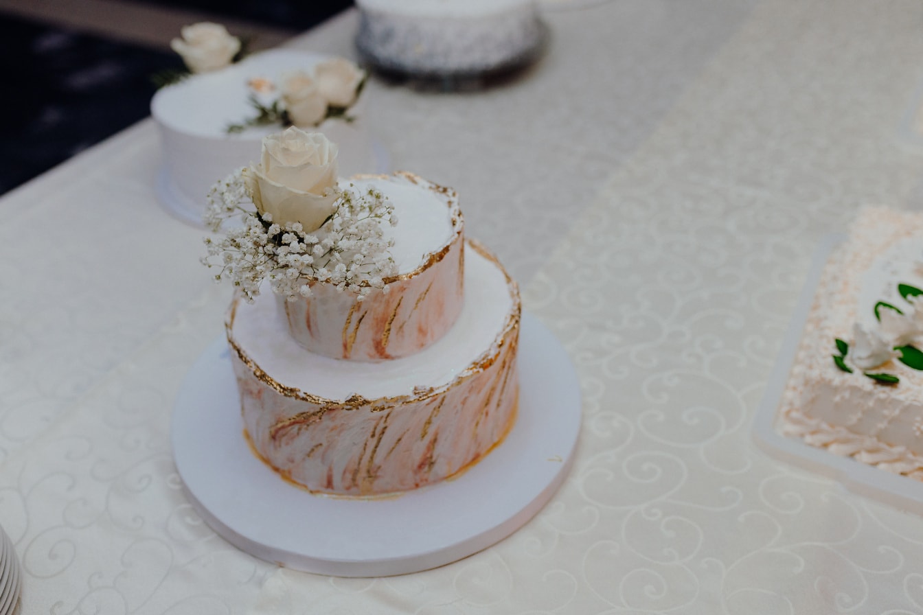 Kake med hvit rosebudblomst på toppen