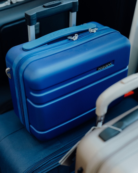 A small blue suitcase on another larger passenger blue suitcase