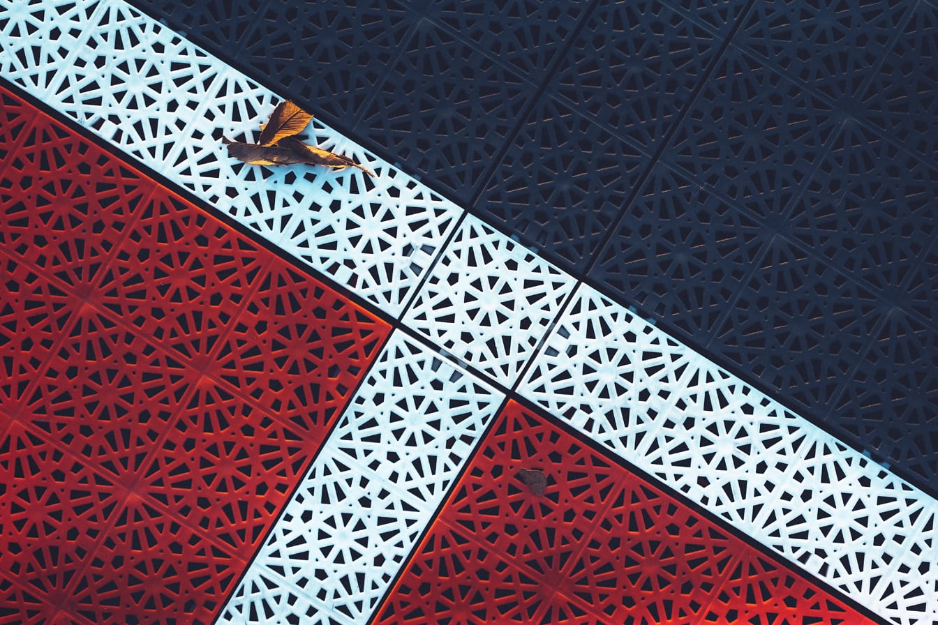 Plastplattor med arabeskdesign färgade i mörkröd och blå färg med vita linjer