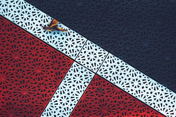 Kunststofffliesen mit Arabeskenmuster in dunkelroter und blauer Farbe mit weißen Linien