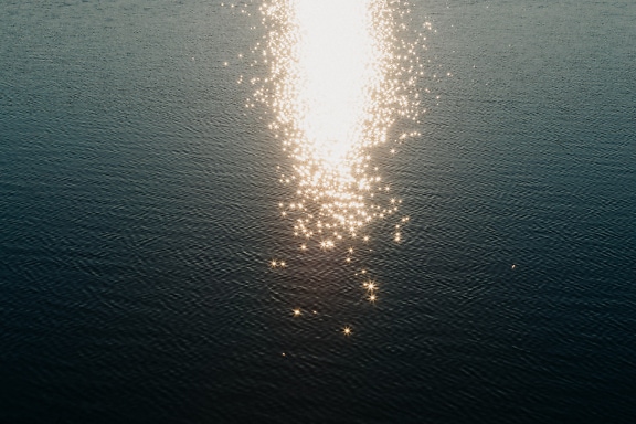 Glitrende solstråler som skinner på vannet