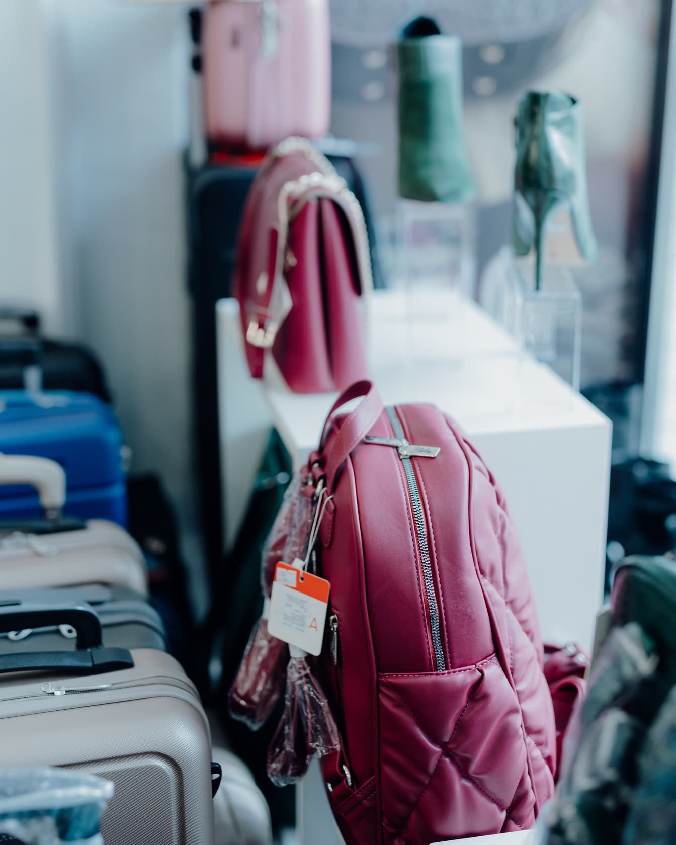 Lyserød fashionabel rygsæk på hylde i butik med andre håndtasker, der tilbydes til salg
