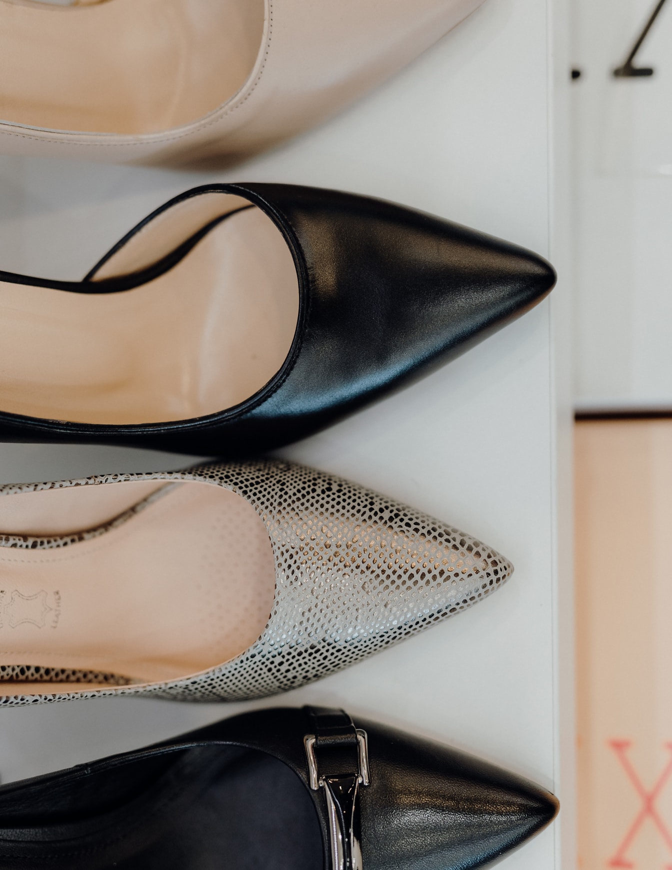 Bézs, fekete és csillogó divatos cipők közelről a polcon