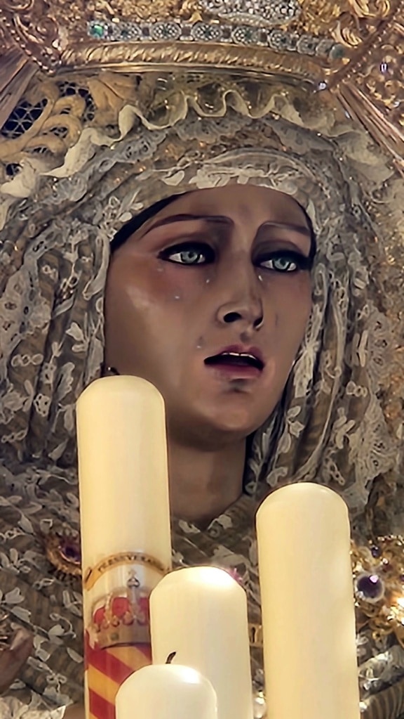 Katolsk staty av en Guds moder med en slöja och vita ljus