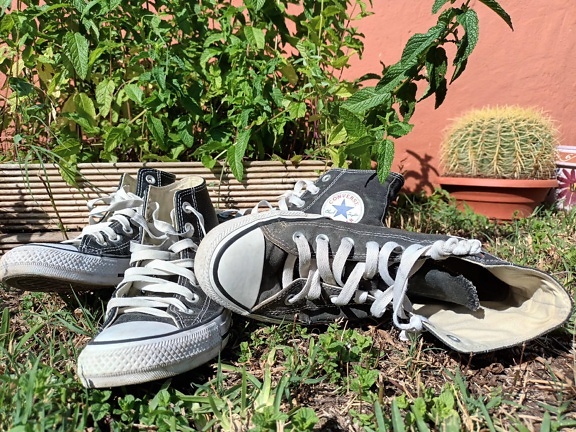 Par sorte og hvide Converse sneakers på jorden