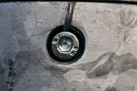 은색 금속 페인트로 칠해진 주철 표면의 구멍에 있는 강철 나사