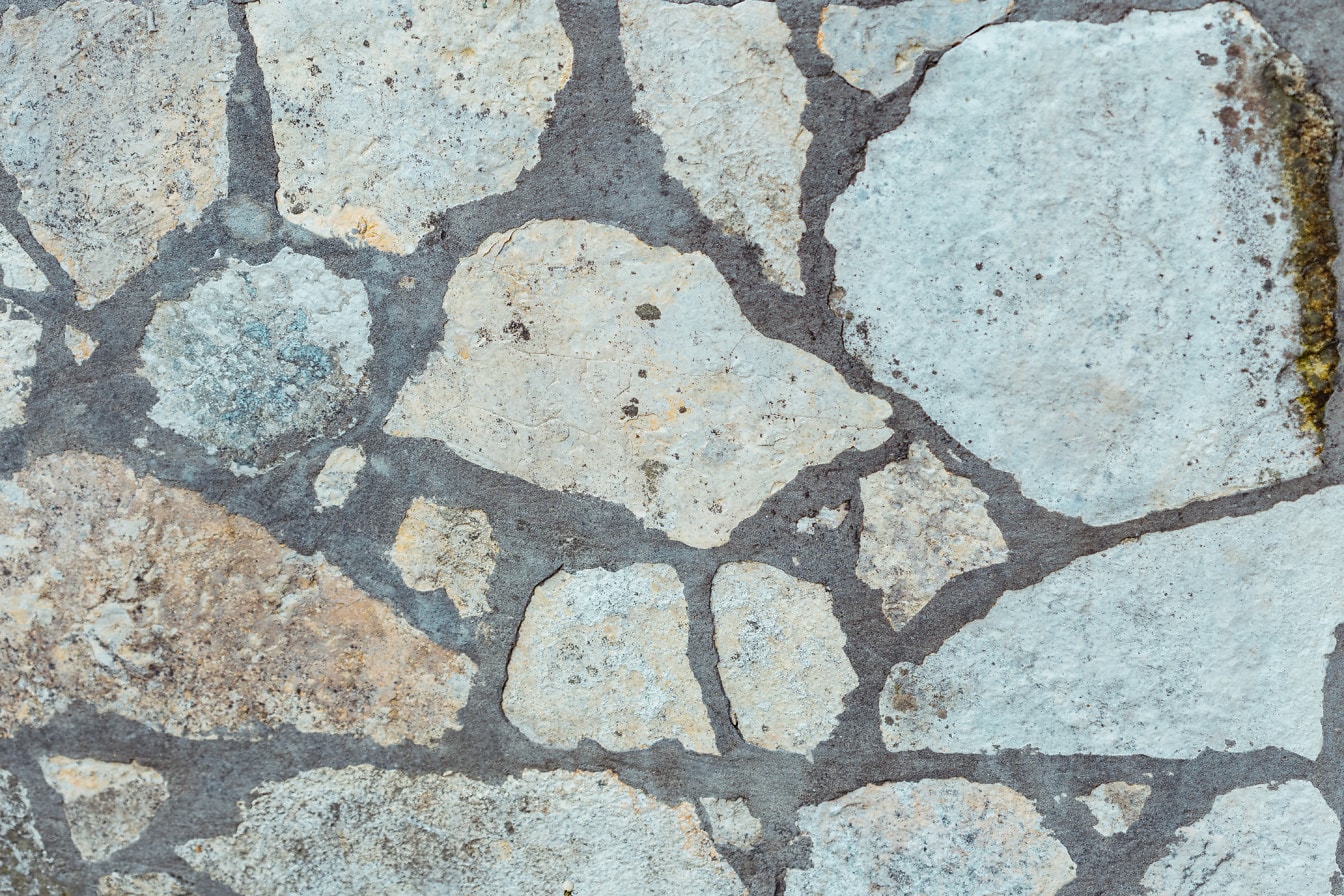 Tekstur close-up dinding batu dengan semen abu-abu