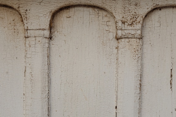 Texture of peeling paint on wooden surface with carved arches
