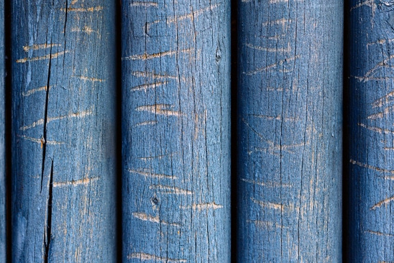 긁힌 자국이 있는 파란색으로 칠해진 나무 통나무의 거친 질감