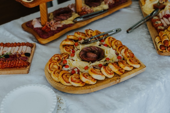 Wooden plate in shape of heart with delicious appetizer food on it