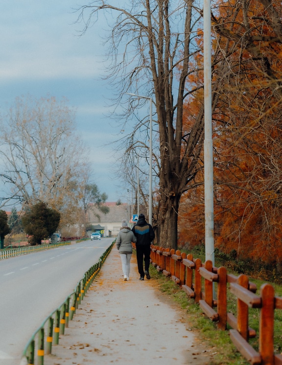 아스팔트 도로 근처의 작은 보행자 통로를 걷고 있는 두 사람
