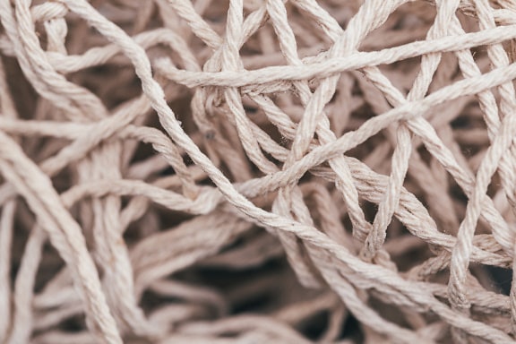 Detailný záber textúry tenkých bielych bavlnených lanových vlákien s uzlami
