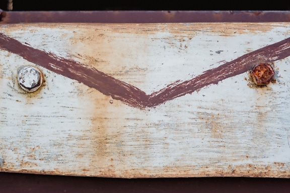 Rusty rectangular metal plate painted in white with metal screws