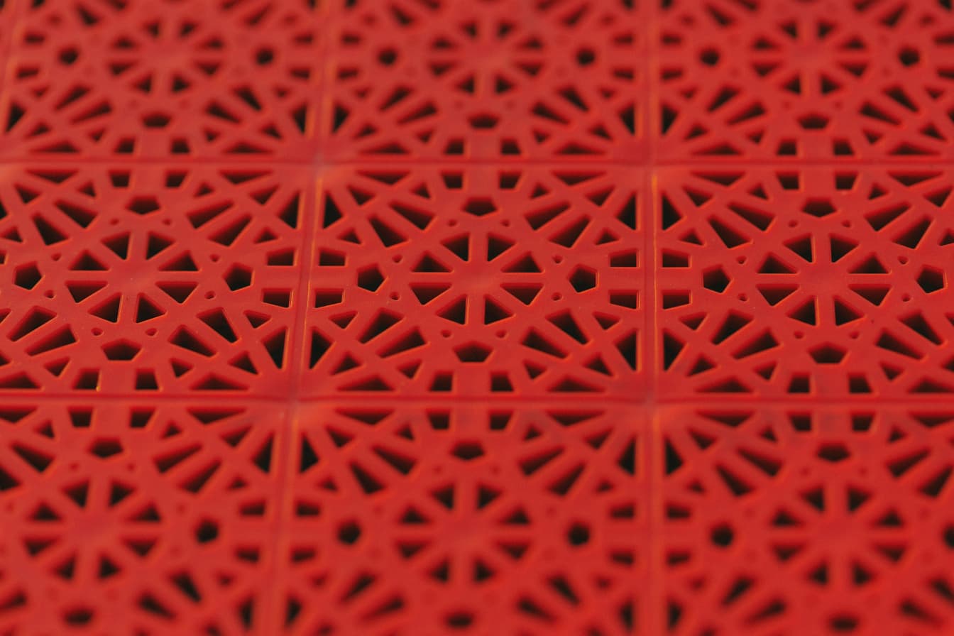 아라베스크 스타일의 기하학적 패턴이 있는 빨간색 플라스틱 표면의 질감