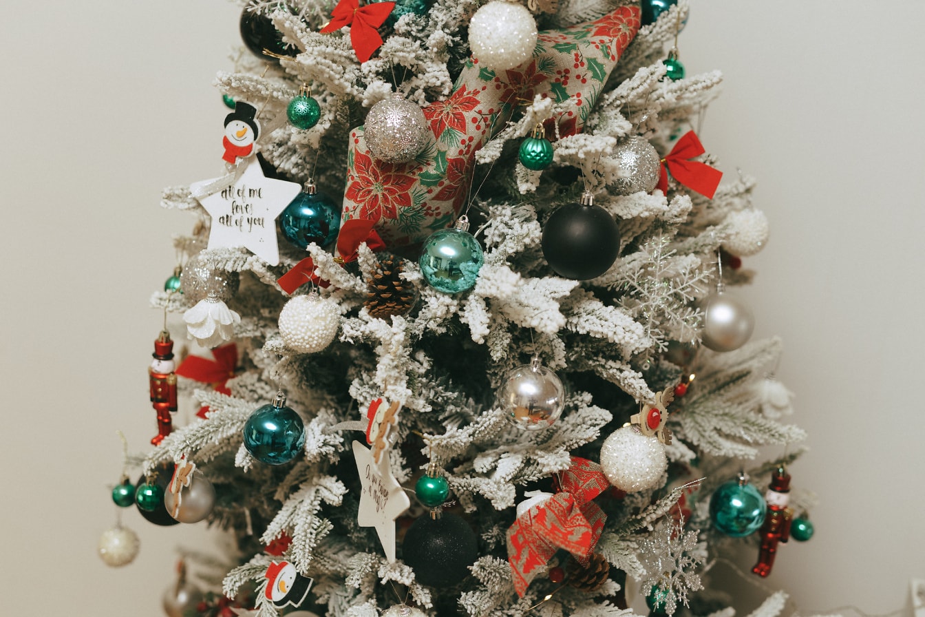 Pomul de Crăciun frumos decorat, cu ornamente și zăpadă artificială pe ramuri