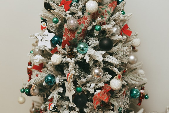 Beautifully decorated Christmas tree with ornaments and artificial snow on branches