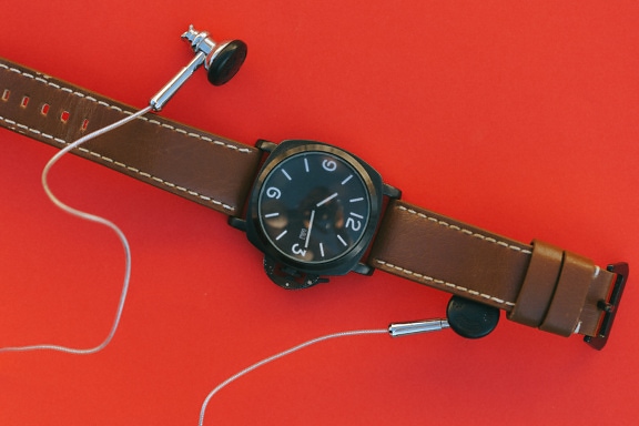 Reloj de pulsera con correa de cuero marrón y auriculares
