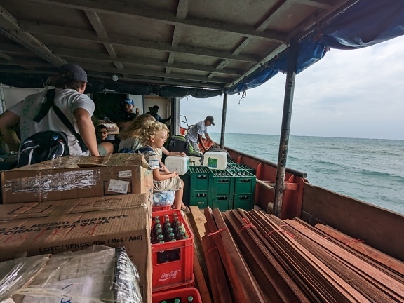 Ludzie podróżujący łodzią, siedzący wśród różnych produktów