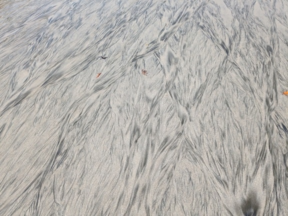 Tekstur av sand og gjørme fra en rennende gjørme på stranden