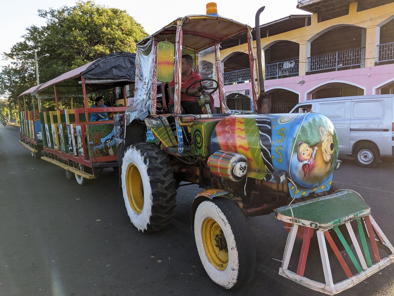 Traktor dengan trailer objek wisata dengan desain dicat di atasnya
