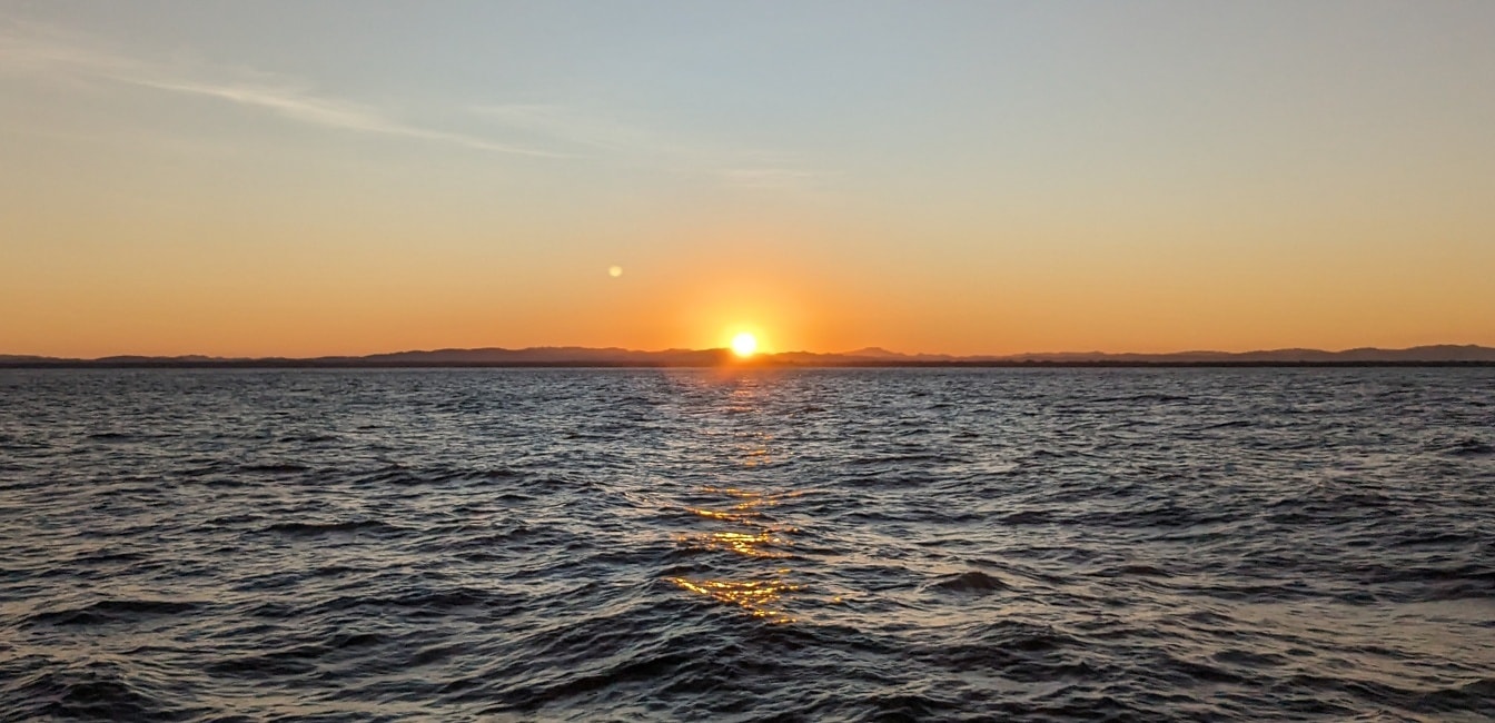 Zonsondergang over oceaanhorizon met zonnestralen als achtergrondverlichting