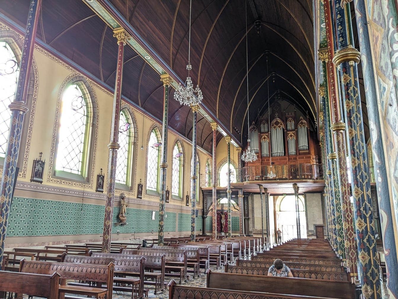 Kostol Panny Márie milosrdenstva s osobou modliacou sa na lavičkách a organových píšťalách v pozadí
