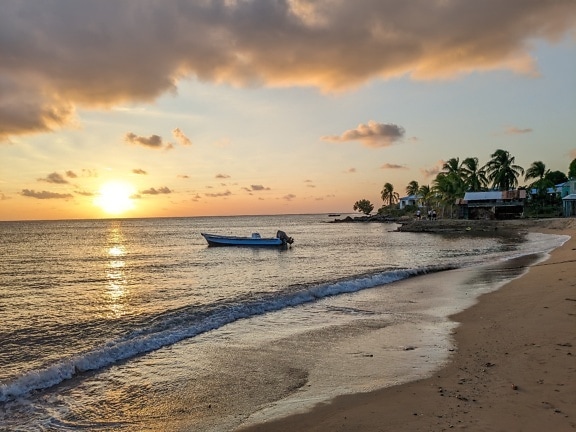 日出时在热带天堂海滩上的水中划船