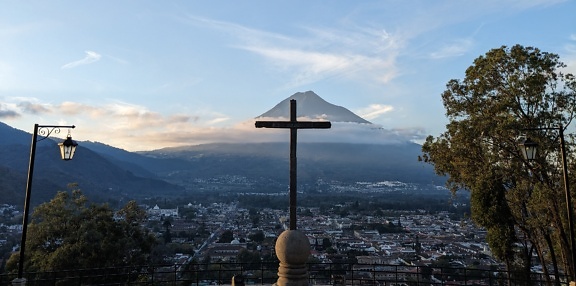 在一根杆子上十字架，背景是危地马拉城市景观的全景