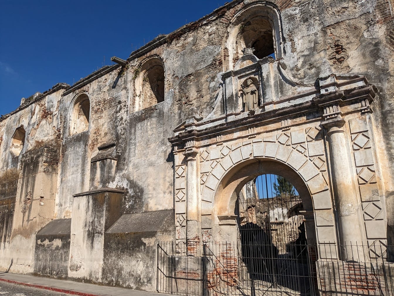 Exteriér staré budovy v Antigue v Guatemale s bránou s litinovým plotem