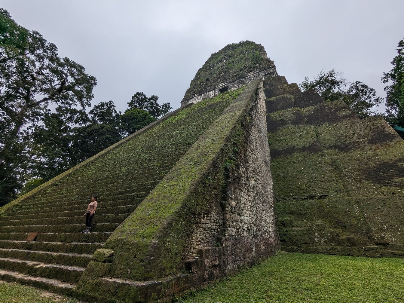 Persona de pie en una escalera de piedra de la pirámide V del templo de Tikal en Guatemala