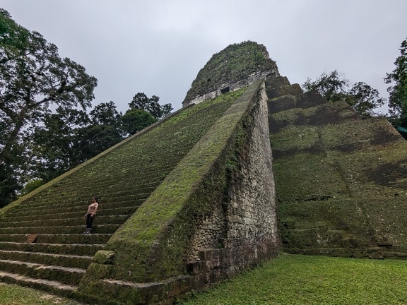 Osoba stojaca na kamennom schodisku pyramídy chrámu Tikal V v Guatemale