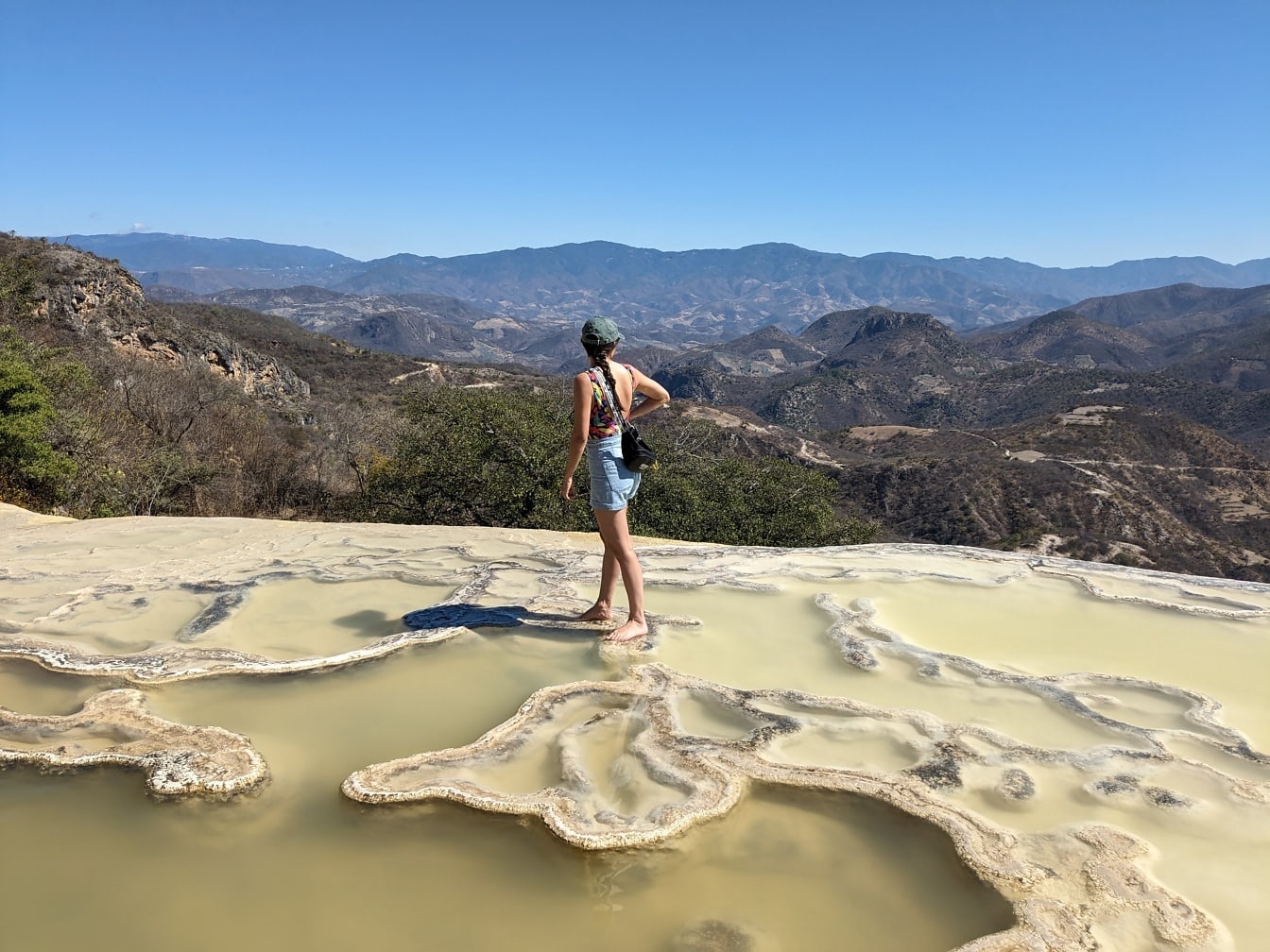 Bosá turistka stojí vo vodnom prameni na vrchole hory