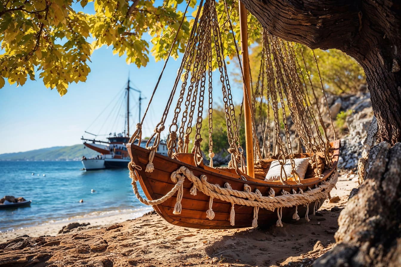 Boat with bed inside hanging from a tree on a beach in Croatia