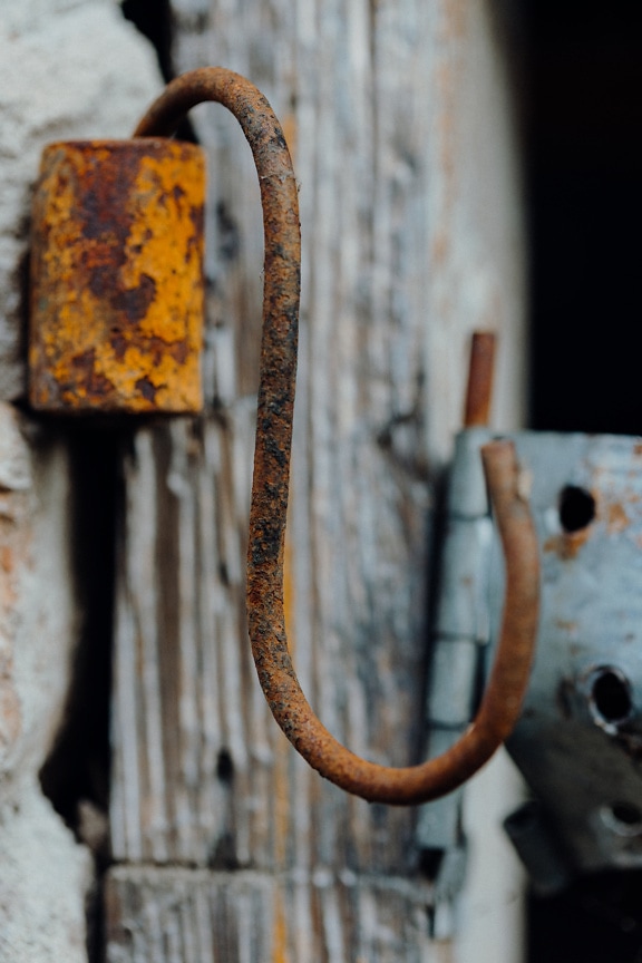 Gancho de metal oxidado colgando de un poste