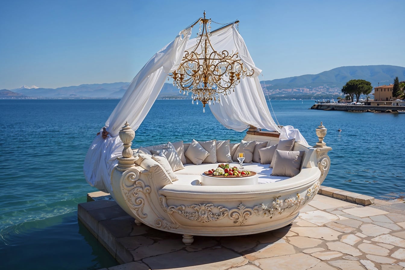 Velká postel oválného tvaru s lustrem v koloniálním stylu na molu v Chorvatsku