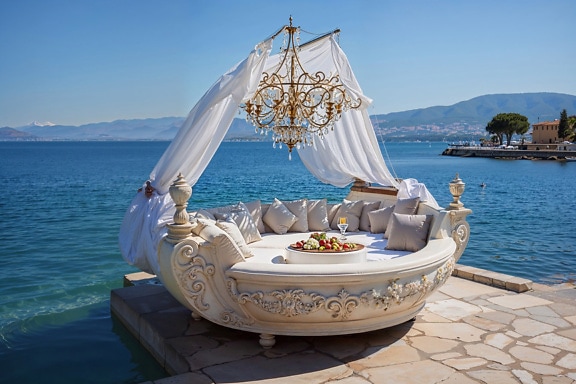 Ovális alakú nagy ágy, gyarmati stílusú csillárral felette egy horvátországi mólón