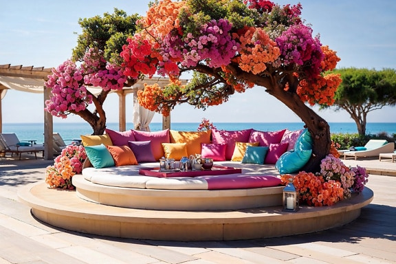 Runde Sitzecke mit bunten Kissen und einem Tisch unter einem blühenden Baum