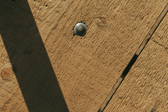 Sekrup baja dengan bagian atas bundar di papan kayu