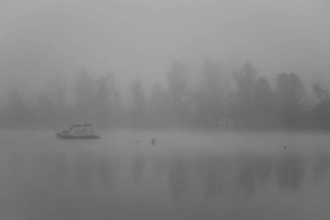 Fekete-fehér fotó kis halászhajóról a sűrű ködben