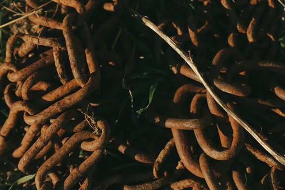Pile of rusty cast iron chains on ground