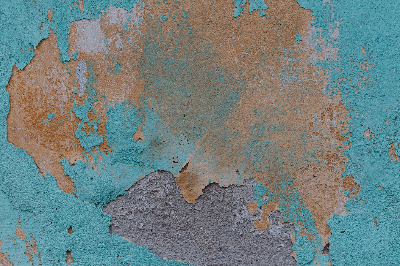 Nazelenalá a nažloutlá barva odpadávající z cementové zdi