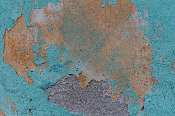 Peinture verdâtre et jaunâtre tombant d’un mur de ciment