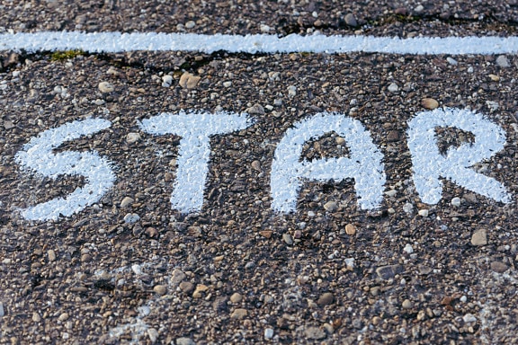 Ordet stjerne, skrevet i hvidt på en asfaltvej