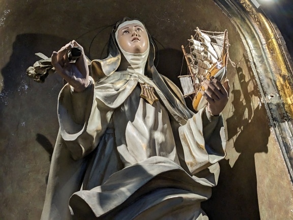 Estátua católica de uma freira segurando um navio