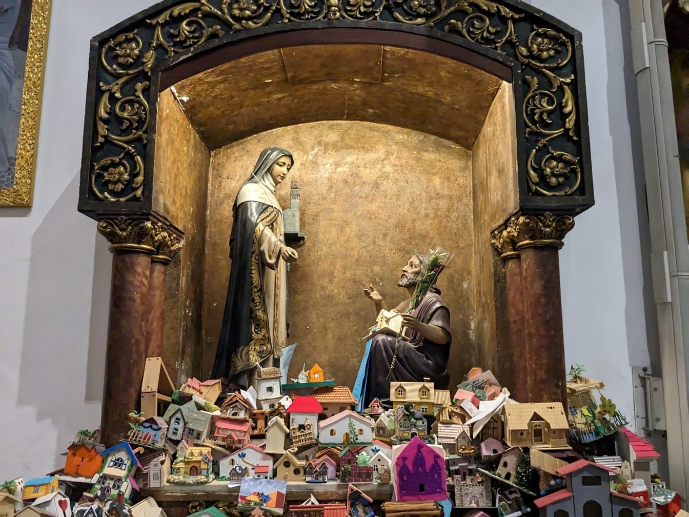 Socha muže a ženy ve výklenku kostela milosti s miniaturními domečky